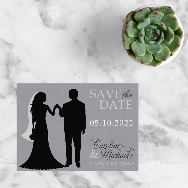 Save the date kaart Silhouet is abstract qua ontwerpstijl, met een silhouet van een bruidspaar, vlak voor de openingsdans, in het middelpunt. Kleuren zijn grijs, zwart en wit.